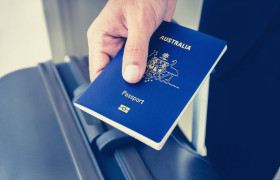 Traveler holding a passport beside a suitcase